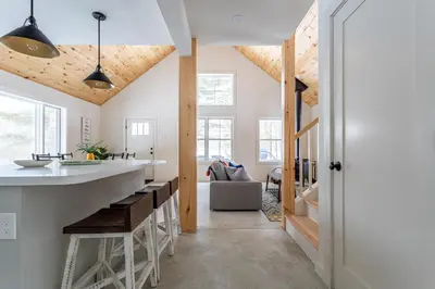 a kitchen with wooden ceilings and a counter with a bar at Lakefront Cabin with Private Dock Kenoza Den in Jeffersonville