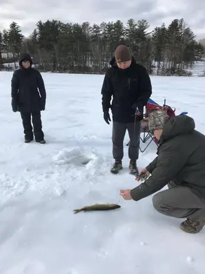 a group of people standing in the snow with a fish at Kenoza Lake Waters wLake AccessCanoeIce-fish in Callicoon