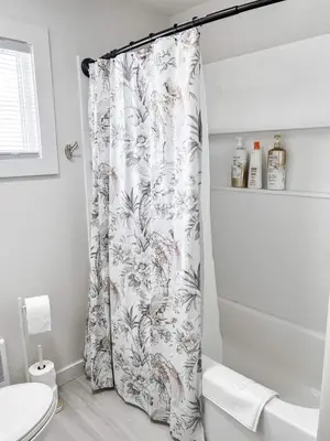a bathroom with a shower curtain and a toilet at Kenoza Lake Waters wLake AccessCanoeIce-fish in Callicoon