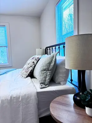 a bedroom with a bed with pillows and a lamp at Kenoza Lake Waters wLake AccessCanoeIce-fish in Callicoon