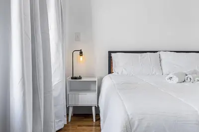 a bedroom with a white bed and a night stand at 3BR Apt Mins to Bus Newark Airport Penn Sta NYC in Hillside