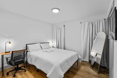 a bedroom with a bed and a mirror and a chair at 3BR Apt Mins to Bus Newark Airport Penn Sta NYC in Hillside