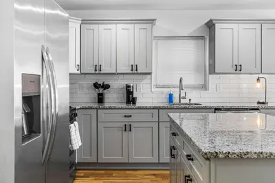 a kitchen with white cabinets and a stainless steel refrigerator at 3BR Apt Mins to Bus Newark Airport Penn Sta NYC in Hillside