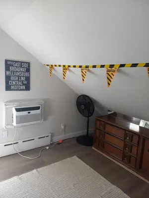 a attic room with a ceiling with flags and a fan at Cozy attic guest room in North Bergen
