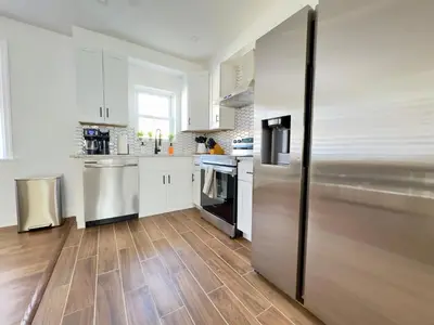 a kitchen with white cabinets and a stainless steel refrigerator at Comfort Philly Stay Jacuzzi and Parking in Philadelphia