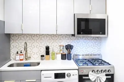 a white kitchen with a stove and a microwave at Manhattan Skyline Views Spacious 3BR in Jersey City