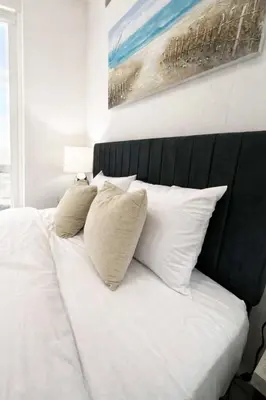 a white bed with a black head board and pillows at Manhattan Skyline Views Spacious 3BR in Jersey City