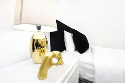 a white bed with a lamp and a yellow object on a table at Manhattan Skyline Views Spacious 3BR in Jersey City