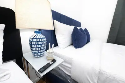 a blue and white bed with a lamp and a remote control at Manhattan Skyline Views Spacious 3BR in Jersey City