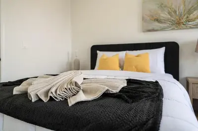 a bed with a black blanket and yellow pillows at 5 beds 7 person Prime Location Near Transit NYC in Jersey City