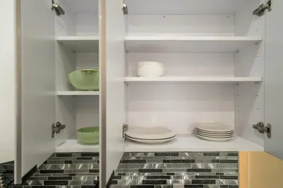 a kitchen with white shelves with plates and bowls at 5 beds 7 person Prime Location Near Transit NYC in Jersey City
