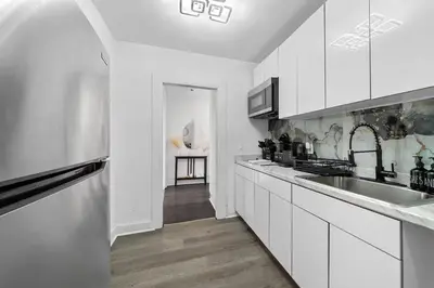 a white kitchen with a sink and a counter at Spacious 3BR NYC Manhattan Skyline Views Nearby in West New York