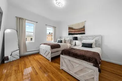 a white bedroom with two beds and a mirror at Bright 4B - Full Kitchen -15 min to Mannhatan in Jersey City