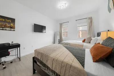 a bedroom with two beds and a desk and a television at Bright 4B - Full Kitchen -15 min to Mannhatan in Jersey City