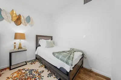 a bedroom with a bed and a table with a lamp at Fast access to NYC - family & group -skyline view in Jersey City