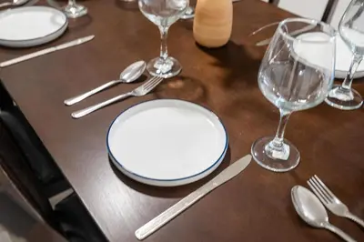 a wooden table with plates and wine glasses on it at 3-Bedroom 5-Beds JC Downtown 19Minutes Time Square in Jersey City