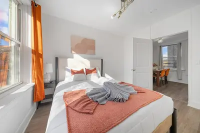 a bedroom with a bed with an orange blanket on it at Modern 2BR Apartment - 15 min to NYC - Sleeps 6 in West New York