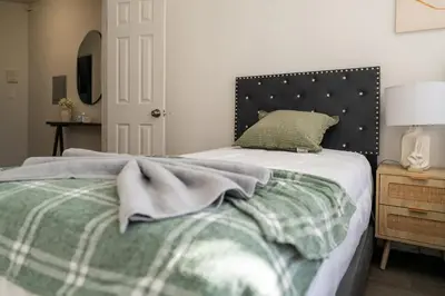 a bedroom with a bed with a green and white blanket at Modern 2BR Apartment - 15 min to NYC - Sleeps 6 in West New York