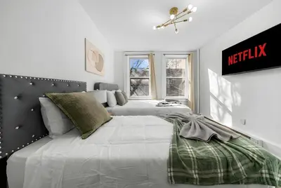 a white bedroom with a large bed and a window at Modern 2BR Apartment - 15 min to NYC - Sleeps 6 in West New York