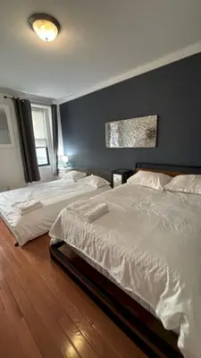 two white beds in a bedroom with a blue wall at Trendy 5-Bedroom Home in NYC Prime Location in New York