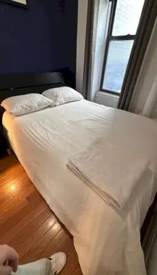 a bed with white sheets in a room with a window at Trendy 5-Bedroom Home in NYC Prime Location in New York