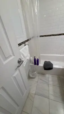 a bathroom with a white tub and a white tile floor at Trendy 5-Bedroom Home in NYC Prime Location in New York