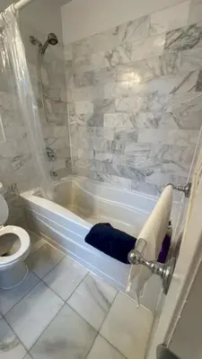 a white bathroom with a tub and a toilet at Trendy 5-Bedroom Home in NYC Prime Location in New York