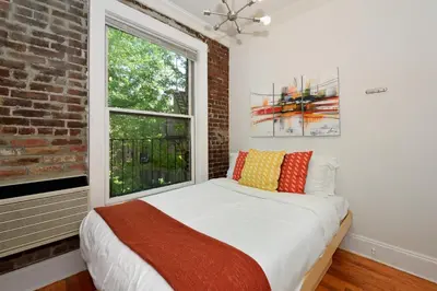 a bedroom with a bed and a window at 10th Avenue Urban Retreat- 3BR NYC in New York