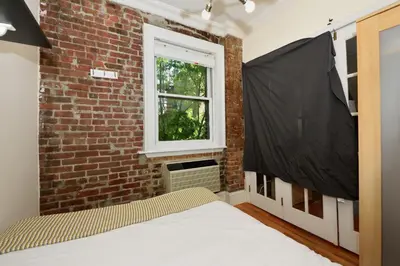 a bedroom with a bed in a brick wall at 10th Avenue Urban Retreat- 3BR NYC in New York