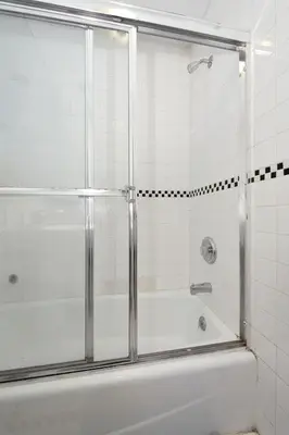 a shower with a glass door in a bathroom at 10th Avenue Urban Retreat- 3BR NYC in New York