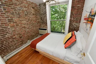 a bedroom with a bed and a brick wall at 10th Avenue Urban Retreat- 3BR NYC in New York