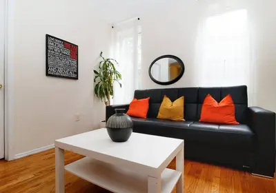 a living room with a black couch with orange pillows at Prime NYC Stay- 3 BR Apartment in New York