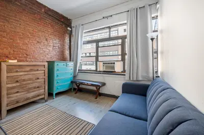 a living room with a blue couch and a brick wall at Prime NYC Stay- 3 BR Apartment in New York