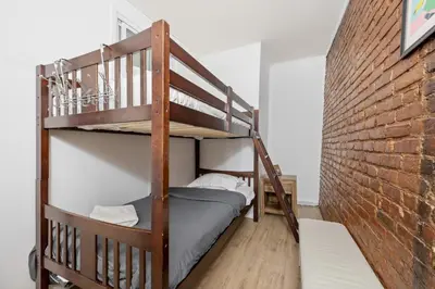 a bedroom with a bunk bed and a brick wall at Prime NYC Stay- 3 BR Apartment in New York