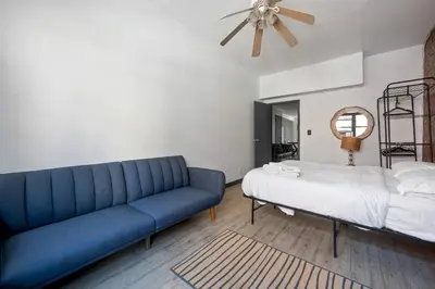 a living room with a blue couch and a bed at Prime NYC Stay- 3 BR Apartment in New York