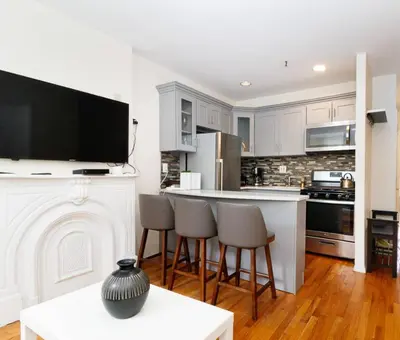 a kitchen with white cabinets and a white fireplace at Prime NYC Stay- 3 BR Apartment in New York