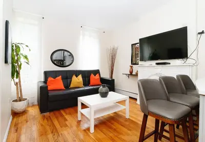 a living room with a black couch and orange pillows at Prime NYC Stay- 3 BR Apartment in New York