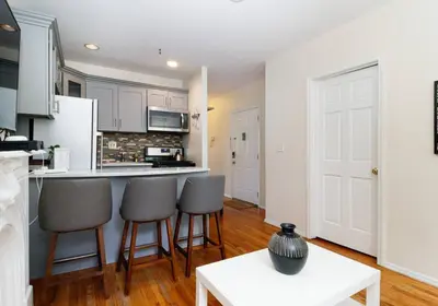 a kitchen with white cabinets and bar stools at Prime NYC Stay- 3 BR Apartment in New York