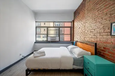 a bedroom with a bed and a brick wall at Prime NYC Stay- 3 BR Apartment in New York
