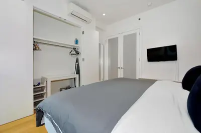 a white bedroom with a bed and a flat screen tv at Time Square Vicinity- Luxury 2BR 2BA NYC Apt in New York