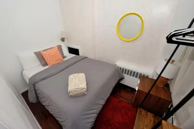 a small bed in a small room with a mirror at Spacious Stay 3 BR in Prime Location of NYC in New York