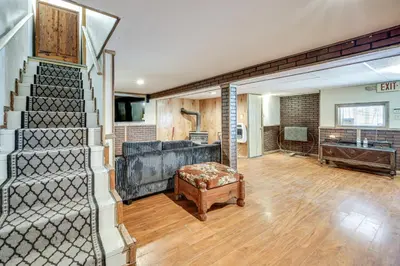 a living room with a staircase and a living room with a couch at Group Getaway with Fire Pit Near Susquehanna River! in Danville