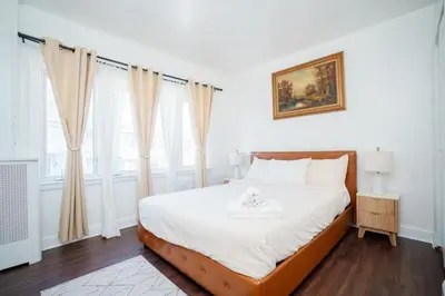 a bedroom with a bed with white sheets and windows at Pet Friendly Jersey City Apartment Near NYC Sleeps 6 with Easy Manhattan Access in Jersey City
