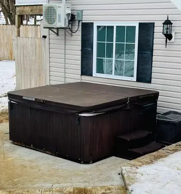 a hot tub sitting outside of a house at Huge house with Game Room, Hot Tub, 3 living rooms, 2 bonus rooms in Albrightsville