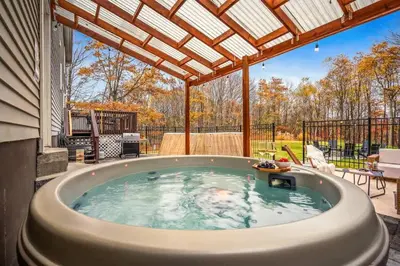 a hot tub in a backyard with a pergola at Luxury Escape 5BR Pool HotTub Game Room FirePit in Long Pond