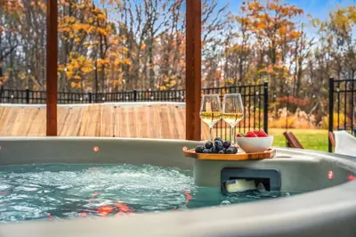 a hot tub with a plate of fruit and wine glasses at Luxury Escape 5BR Pool HotTub Game Room FirePit in Long Pond