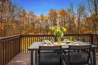 a table with chairs and a vase of flowers on a deck at Luxury Escape 5BR Pool HotTub Game Room FirePit in Long Pond