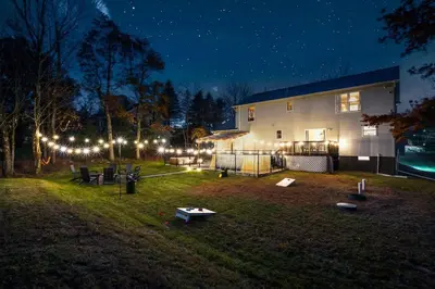 a house with lights in the yard at night at Luxury Escape 5BR Pool HotTub Game Room FirePit in Long Pond