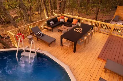 a deck with a table and a couch and a pool at Retreat HotTub FirePit Sauna GameRm Pool Playroom in East Stroudsburg