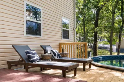 two benches sitting on a deck next to a pool at Retreat HotTub FirePit Sauna GameRm Pool Playroom in East Stroudsburg